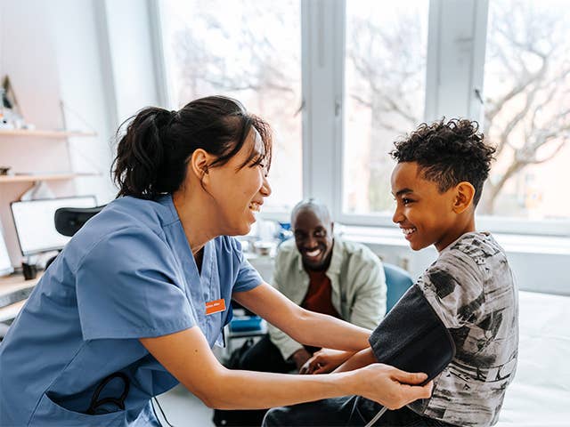 A nurse assists a young boy in measuring his blood pressure in a clinical setting.