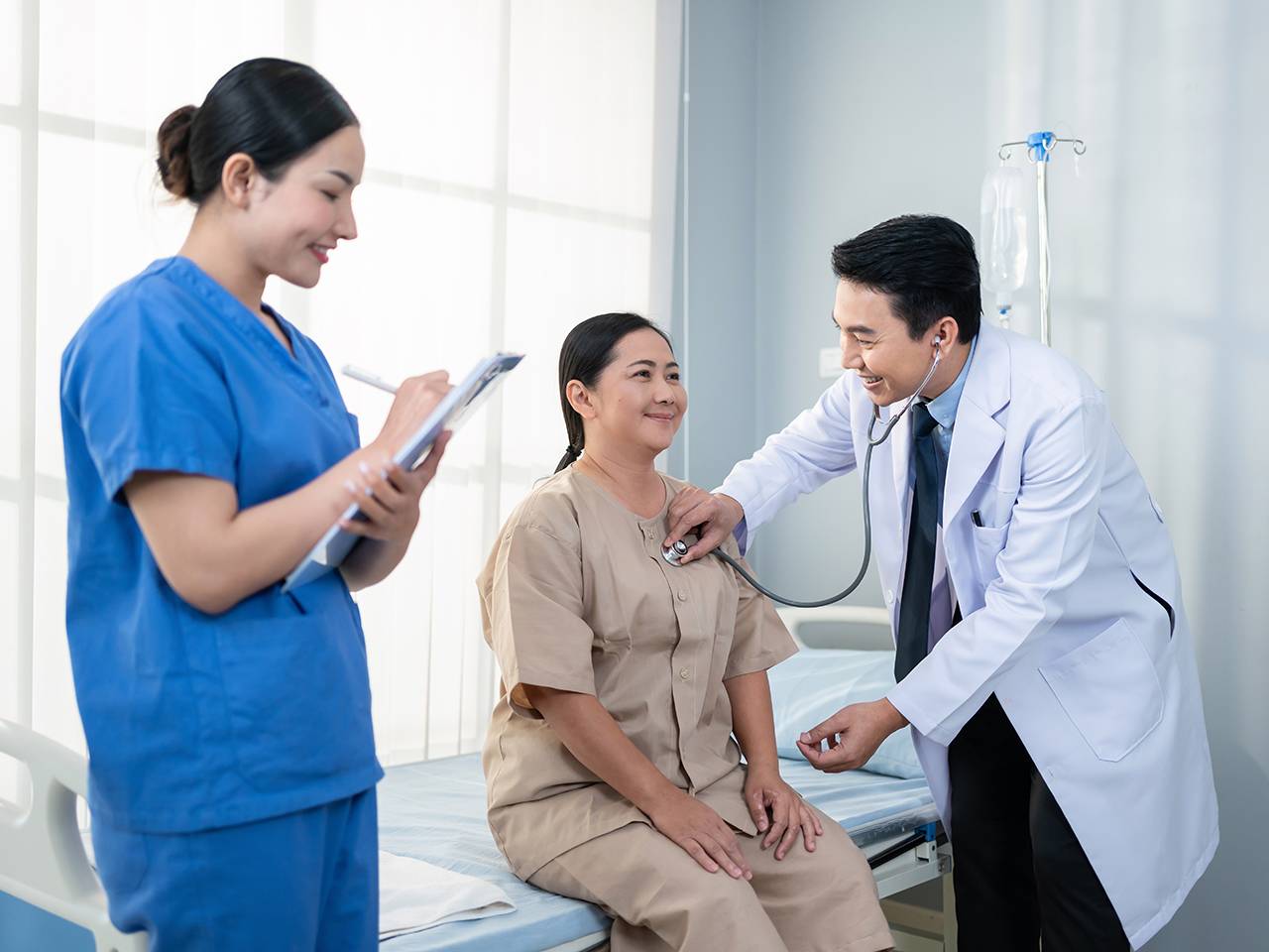 A doctor converses with a patient in a hospital room, discussing the patient's health and treatment options.