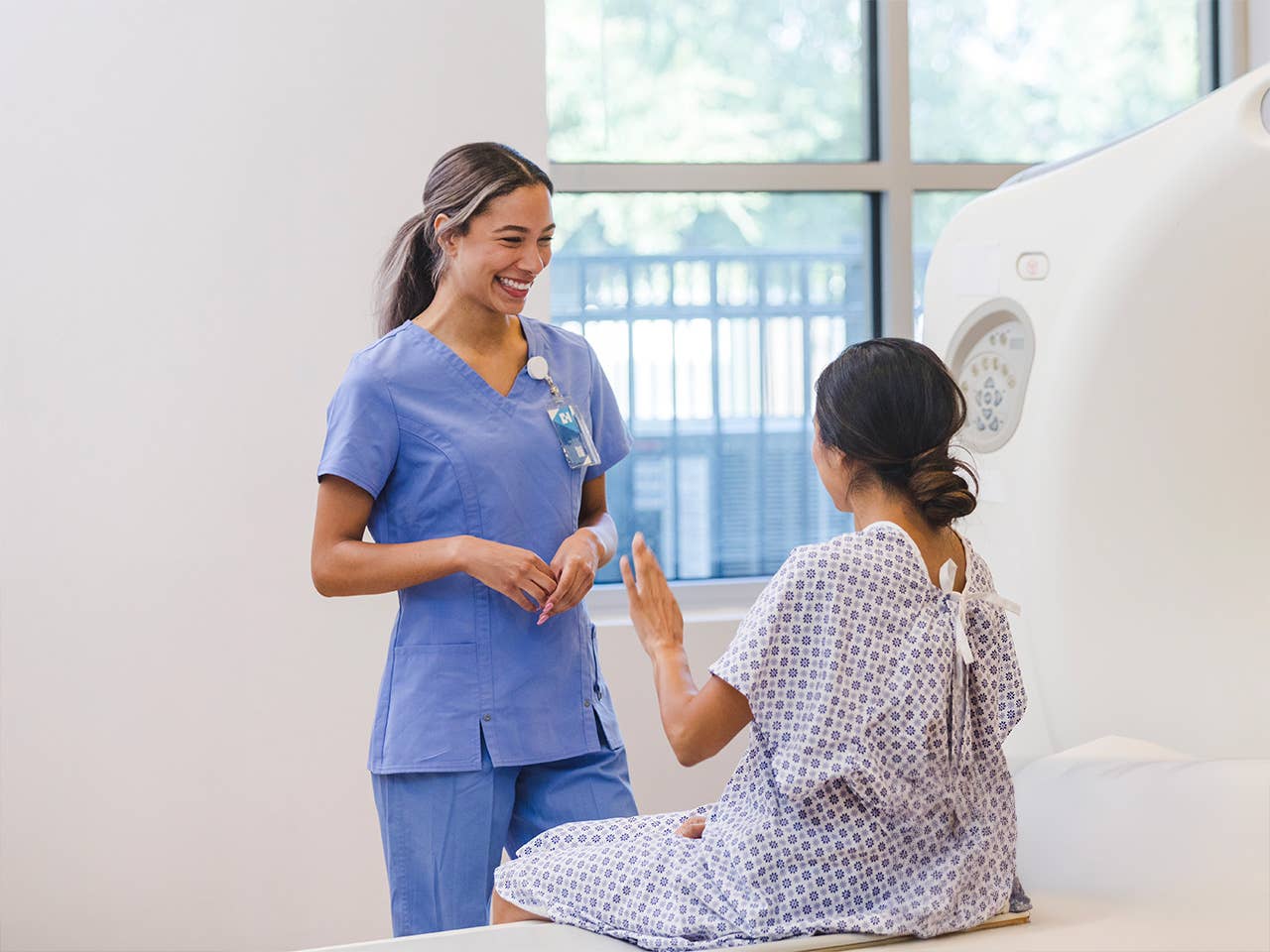 Smiling Corewell Health imaging specialist speaks with a patient before she has an MRI scan