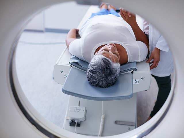 Woman with short grey hair comfortably lies down for a CT scan at a Corewell Health imaging facility