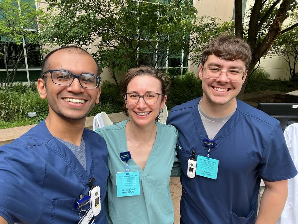 Visiting medical students in scrubs posing together outdoors at a Corewell Health campus