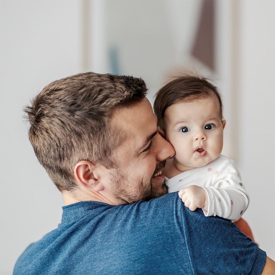 Caregiver holding an infant indoors, highlighting protection and prevention of RSV in babies and young children.