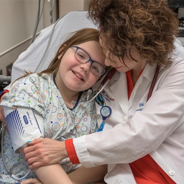 Doctor in lab coat hugs preteen girl patient