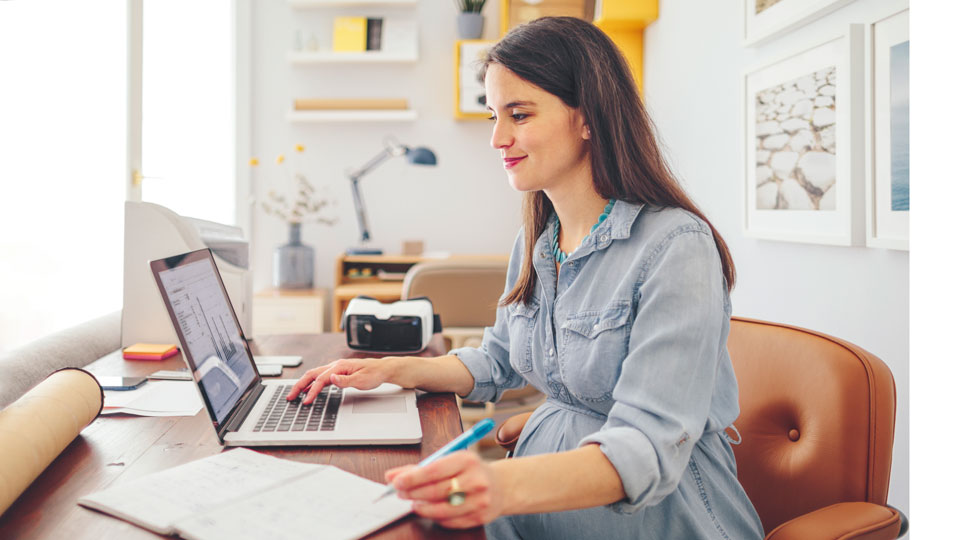 Young woman wearing a light blue blouse sitting with a laptop computer at a table