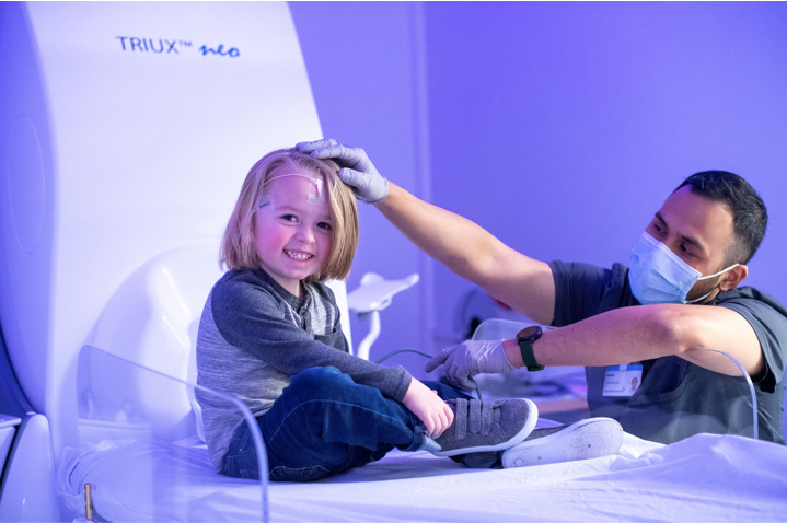 little girl smiles as nurse examines her head