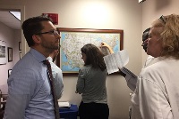 A group of faculty members engaged in discussion within an office setting, representing Graduate Medical Education in Southeast Michigan.