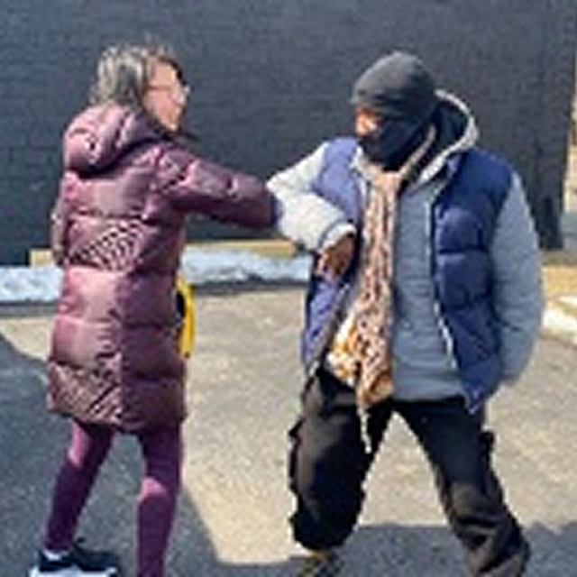 A man and woman stand together in a parking lot, symbolizing community engagement and diversity in CPR training initiatives.