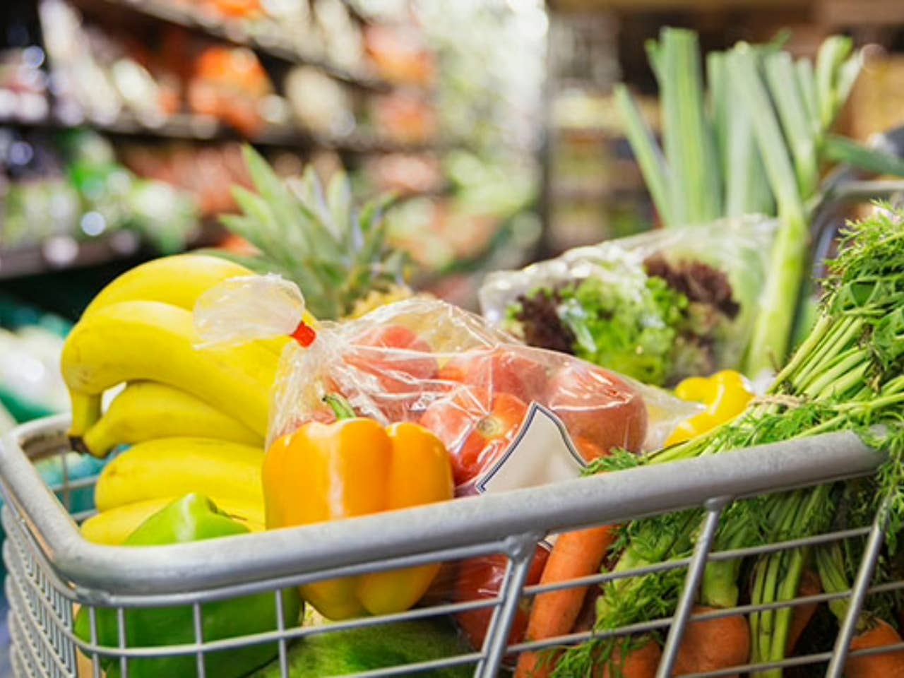Grocery cart filled with produce in a grocery store