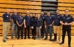 A group of Corewell Health cardiology fellows and attendings in blue shirts volunteering at a gym for Student Heart Check.