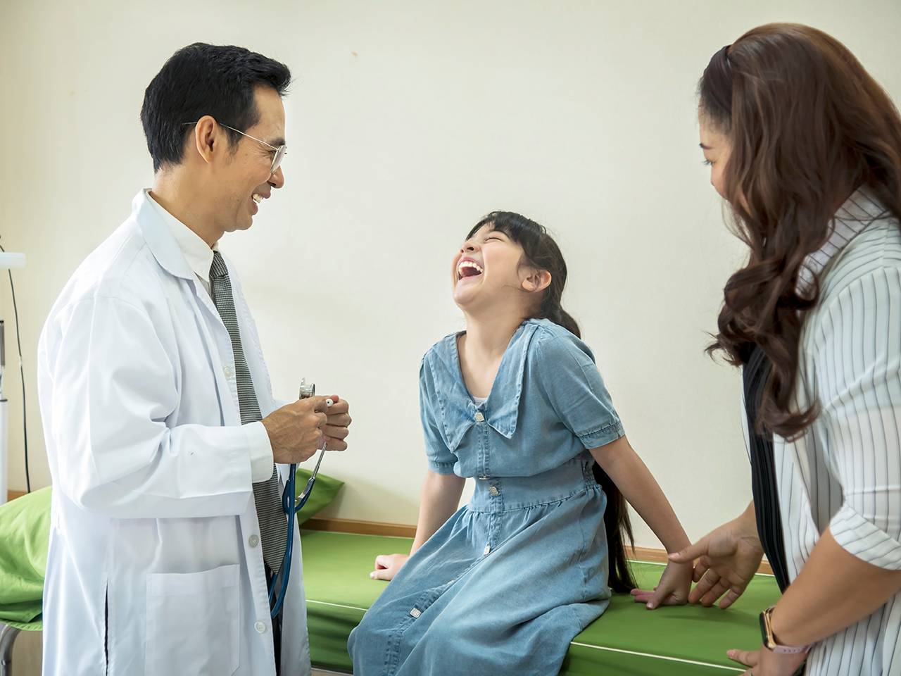 A doctor is speaking with a young girl in a medical office, providing care and guidance.