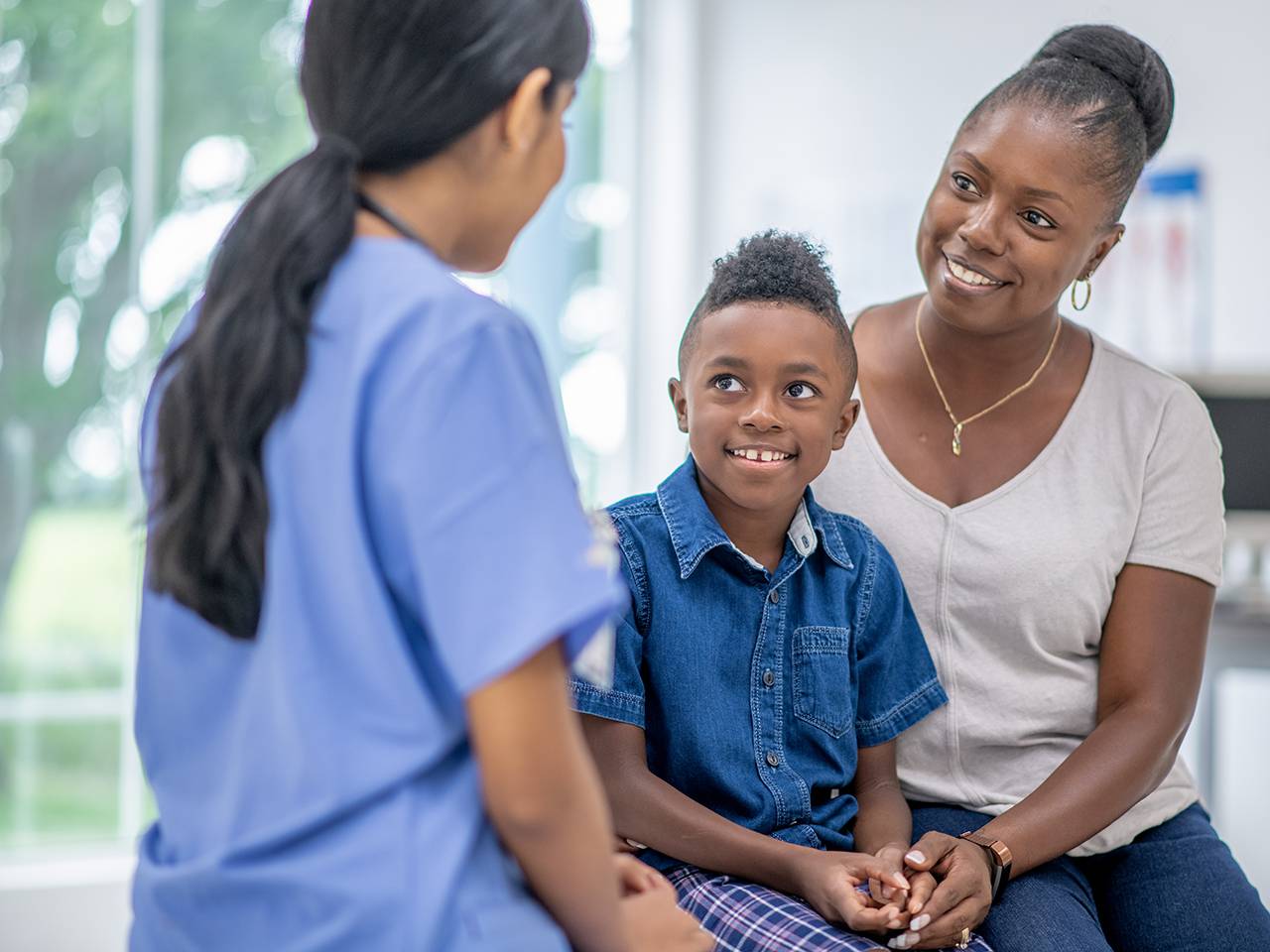 A mother and child sitting together engaged in conversation with a physician.