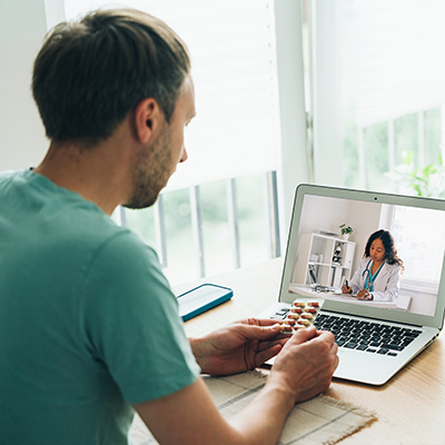 Man in green shirt speaks with a provider in video chat on his laptop