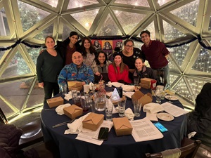 A group of individuals engaged in discussion around a table inside a dome during a journal club event.