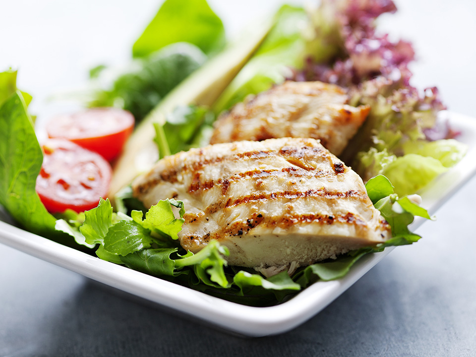 Chicken on top of a plated salad