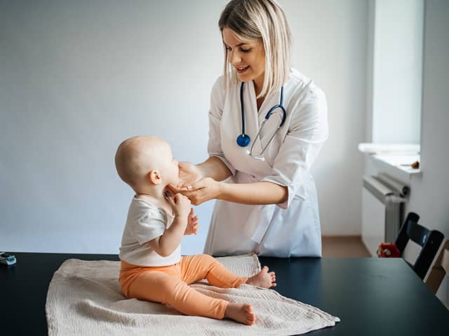 A doctor holds a baby, showcasing a nurturing and caring expression.