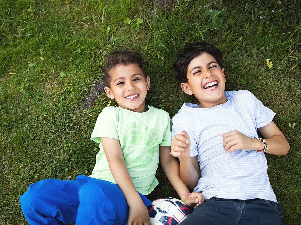 Smiling boy and girl lay next to one another in the grass
