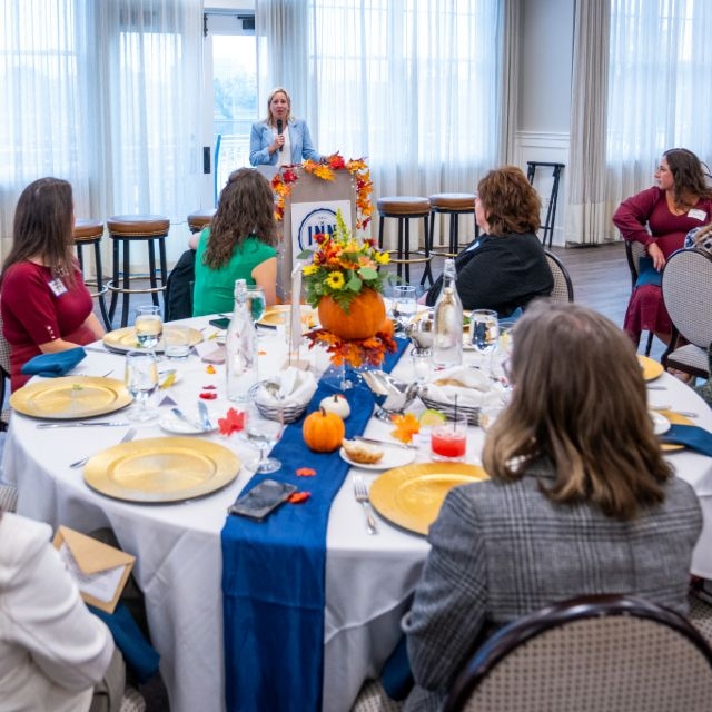 Panel members and attendees listen to the hospitals president speaking during an event