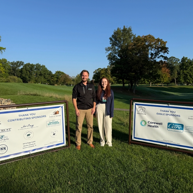 Photo of two teams members standing in the grass between two sponsor banners