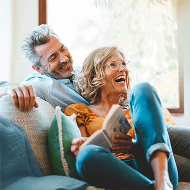 Older man sits on couch hugging his wife