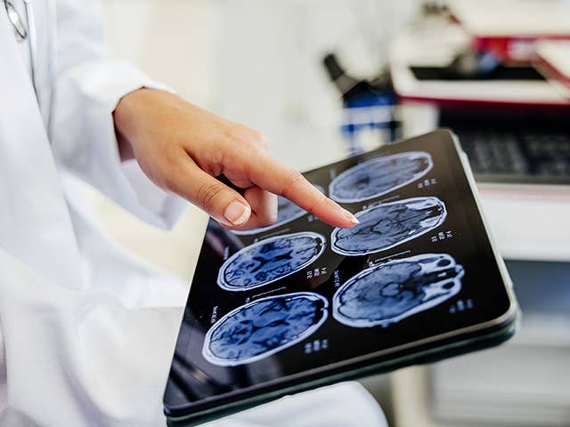 Close up of a primary care doctor's hand looking a scans of a patient's body on a tablet