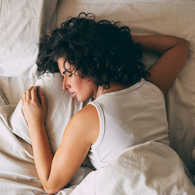 New mother lies on her stomach in a bed sleeping