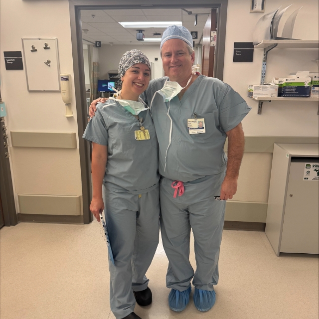 A doctor and resident posing for a picture after a surgery