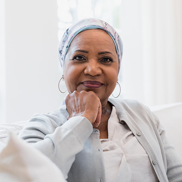 Woman with a hard scarf is sitting and paying attention to an oncology class she is attending at the hospital.