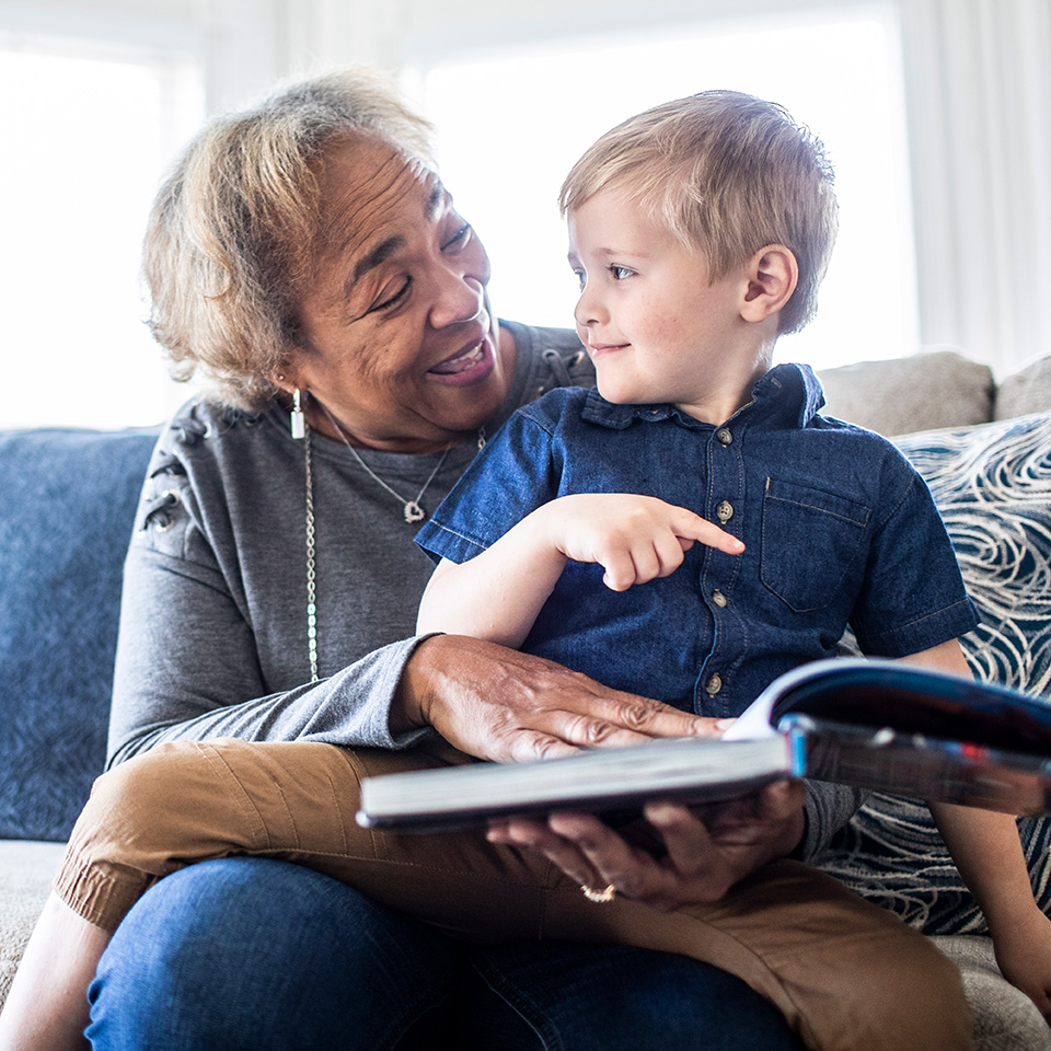 Smiling elderly woman reads a book to a young boy