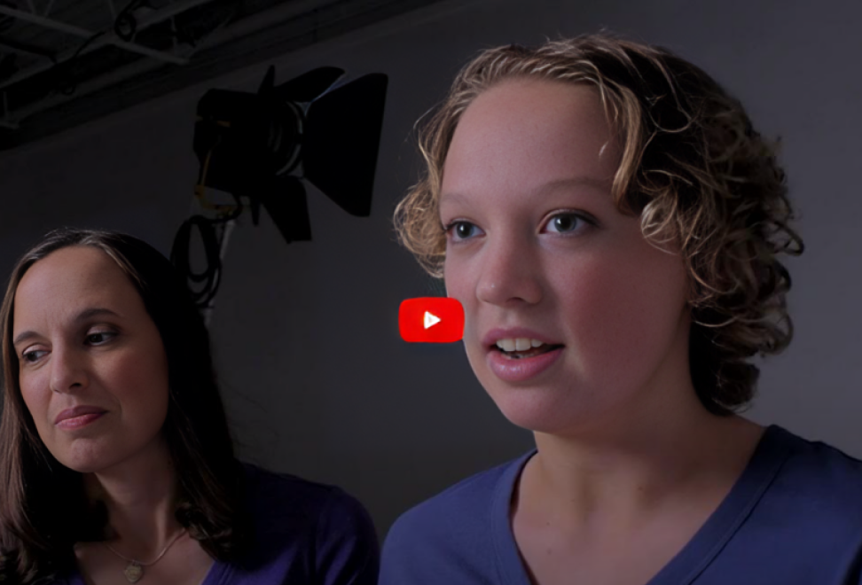 Teenage girl with short hair in a dark blue shirt in front of dark background