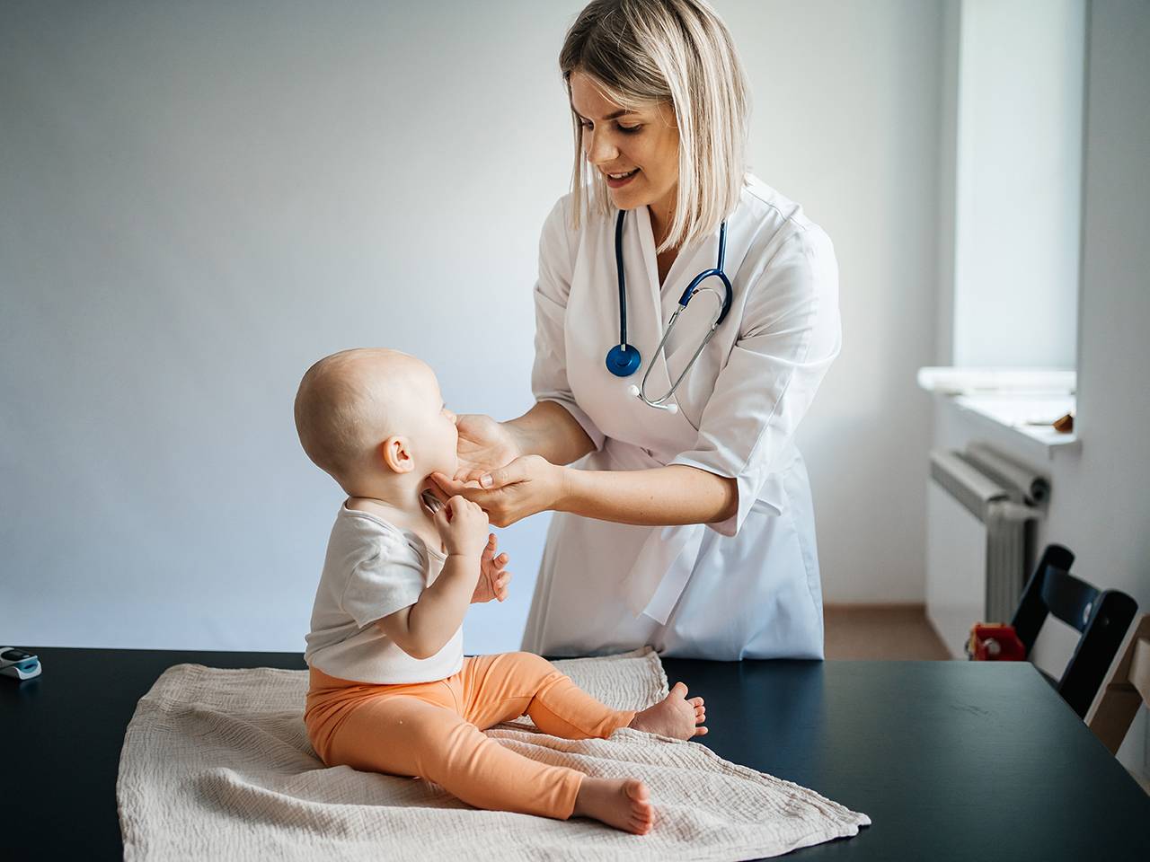 A doctor holds a baby, showcasing a nurturing and caring expression.