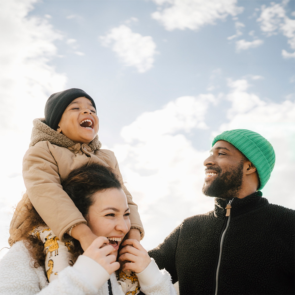 Smiling young boy sits on shoulders of his mom