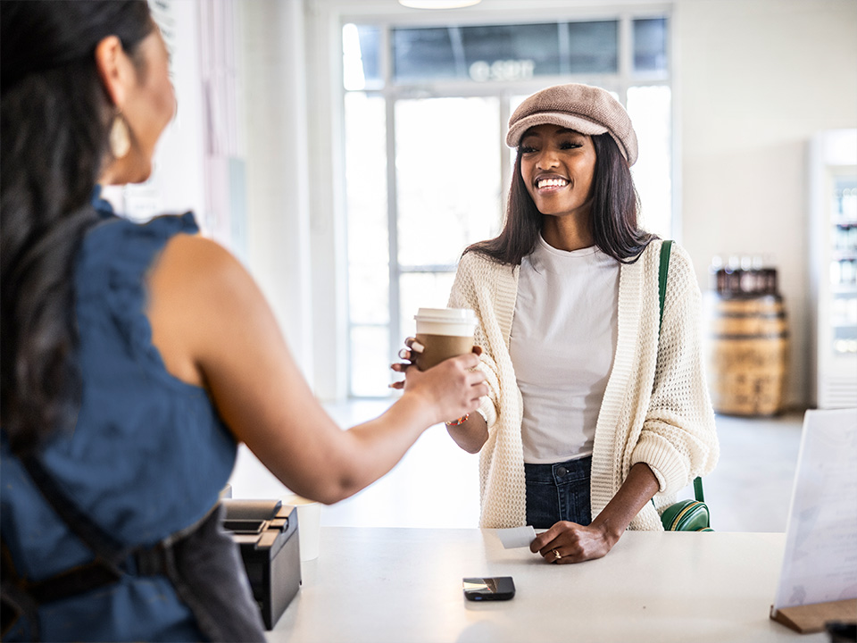 customer grabbing their coffee order from the coffee shop employee