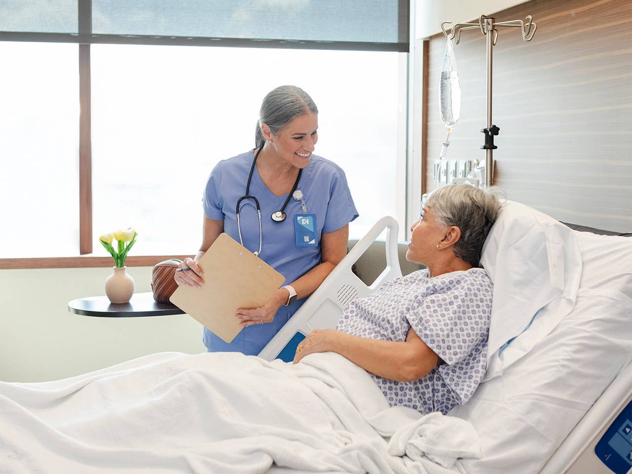 Hospital worker standing at the bedside of a patient and talking