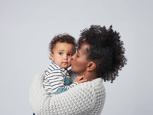 Person holding and kissing an infant, highlighting nurturing care and protection for babies and young children.