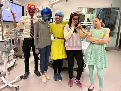A group of individuals in costumes smiles and poses together for a photograph, showcasing creativity and camaraderie.
