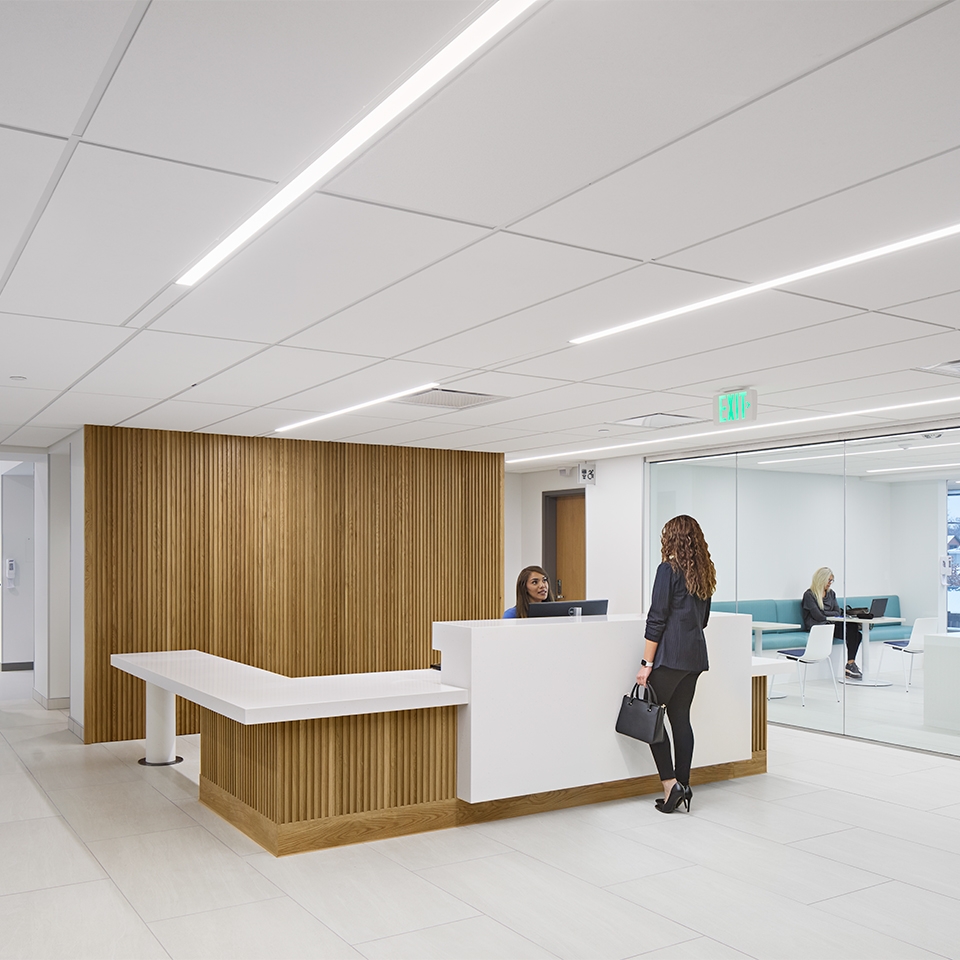 A woman positioned at office reception desk, ready to assist visitors.