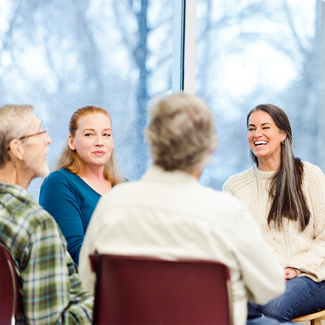 Copilot said:  Transplant support group participants seated in a circle during a discussion in a community meeting room.