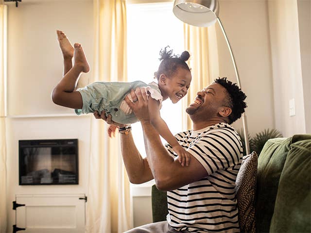 Father and his young daughter playing at home while laughing and smiling.