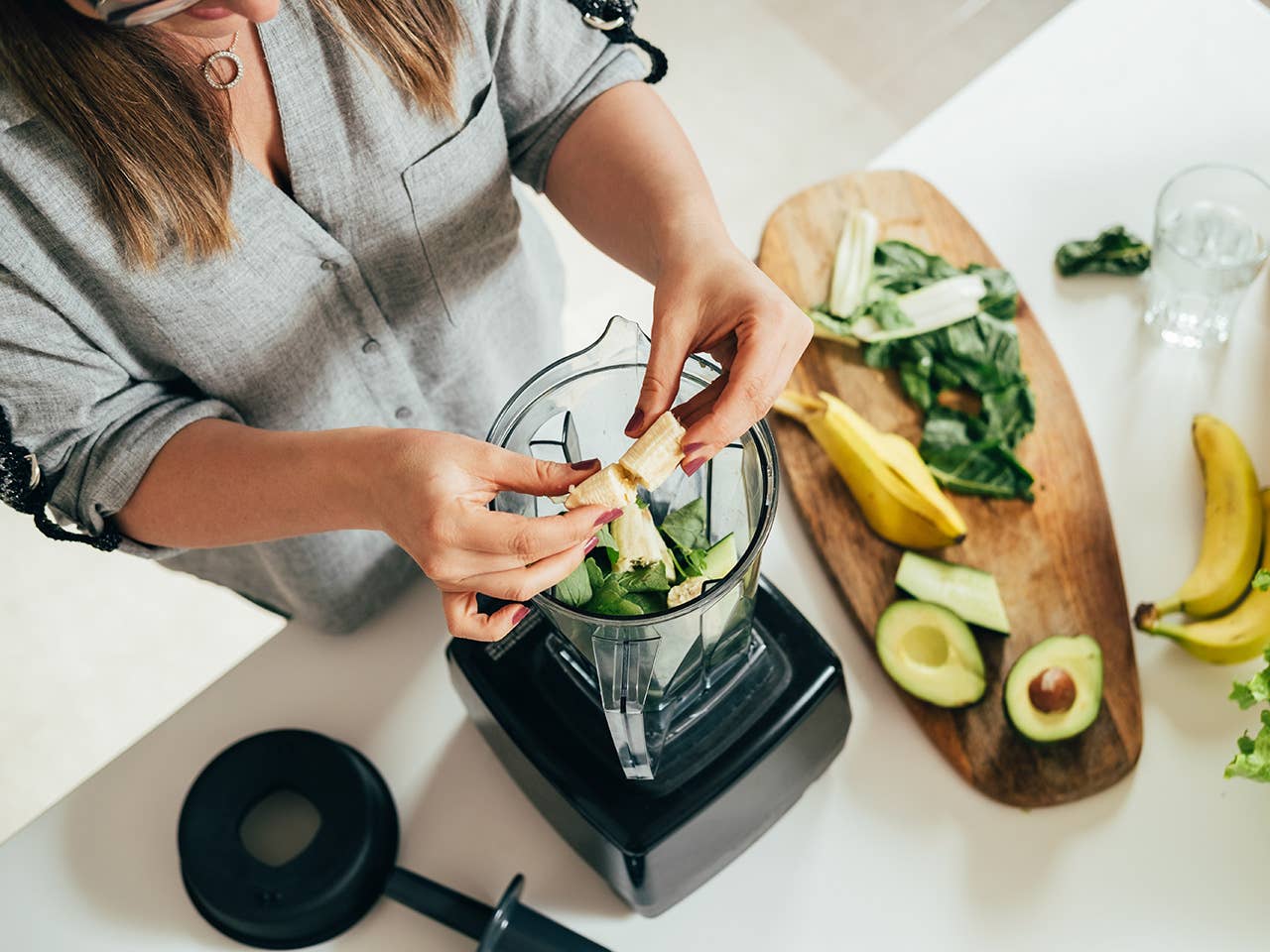 Woman's hands putting fruit in a blender to make a smoothie