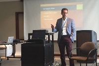 "A man stands confidently before a presentation screen, representing Graduate Medical Education in Southeast Michigan residencies.