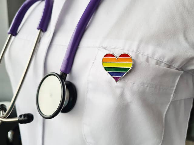 Close up of a rainbow heart pin on a doctor's white lab coat