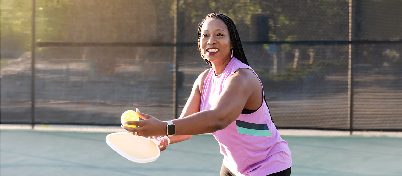 Shoulder pain relief for active adults playing pickleball on an outdoor court with paddle and ball in hand.