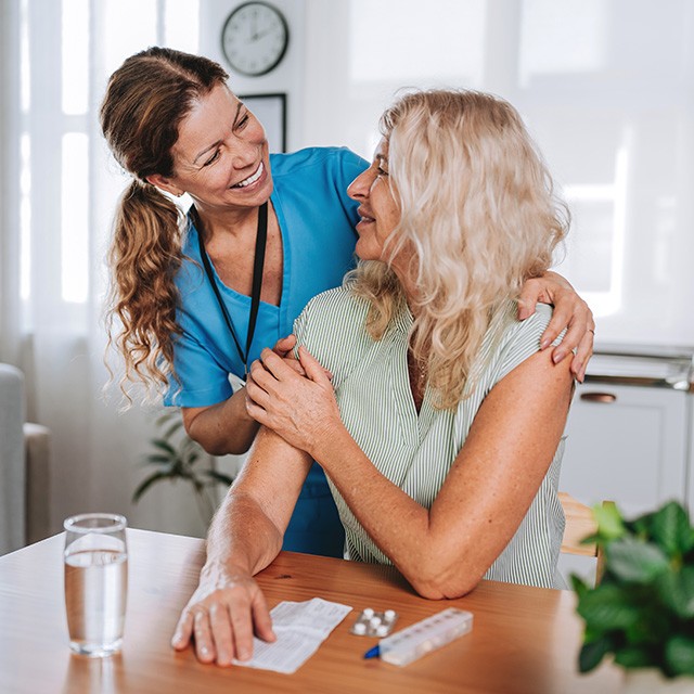 female patient sitting at a table talking through something with a smiling care provider