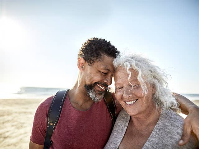 Smiling man with arm around a smiling woman's shoulder as they hug