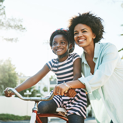 African American woman helps an African American girl ride a bike