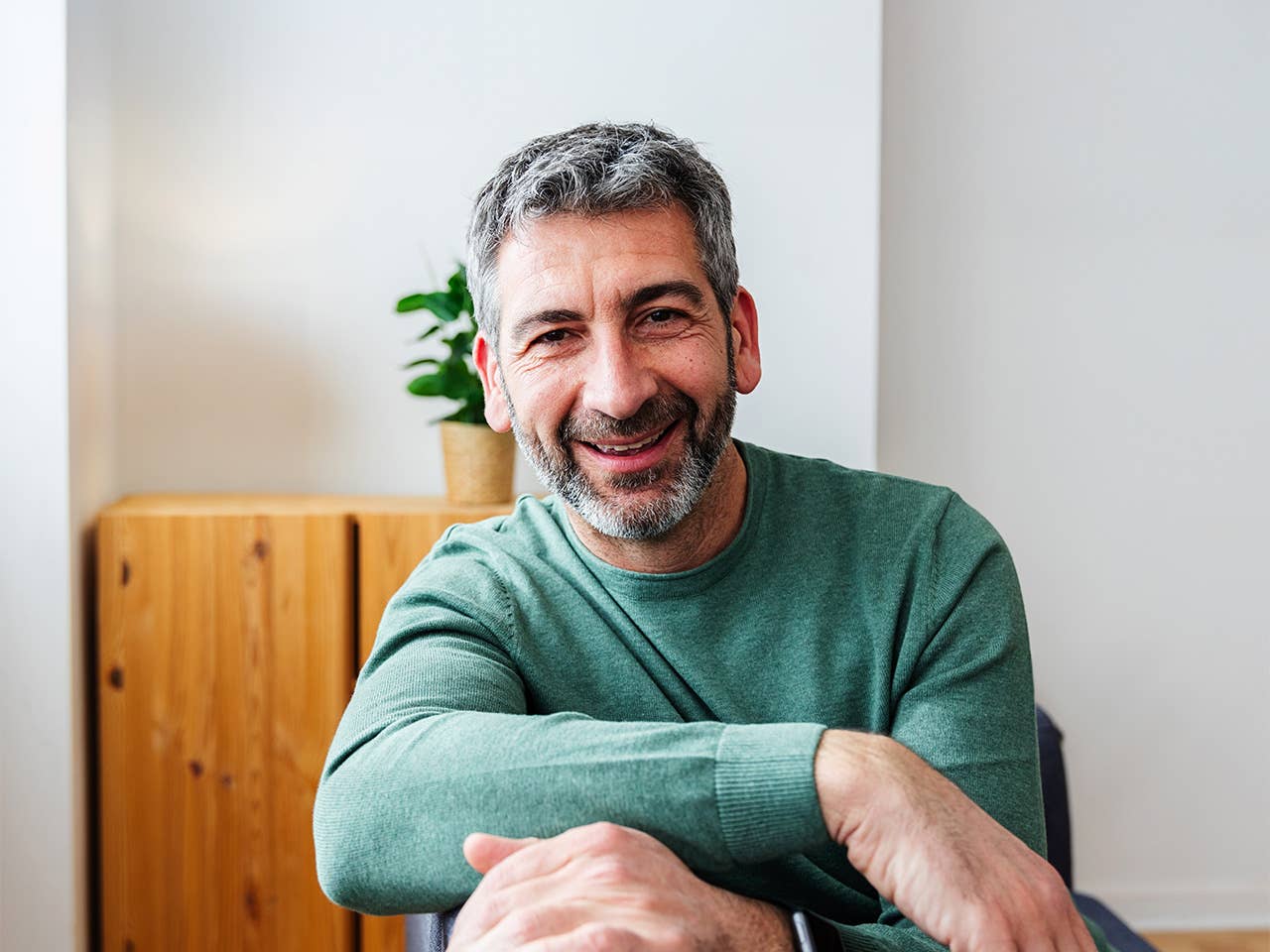A man sitting in a chair, smiling warmly.