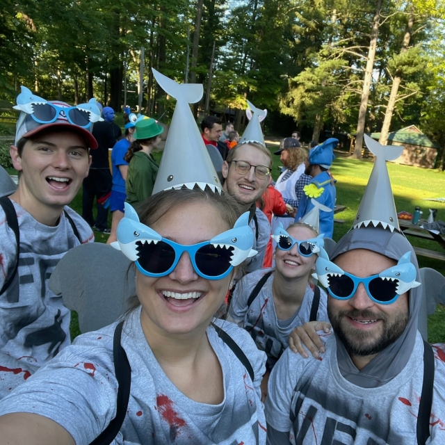 Group photo of residents in goofy hats and glasses outside during an outdoor retreat event