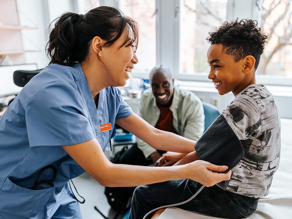 A nurse assists a young boy in measuring his blood pressure in a clinical setting.