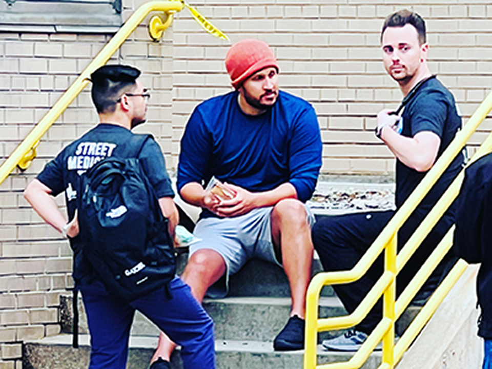 A group of men seated on building steps, engaged in conversation, reflecting community involvement and support initiatives.
