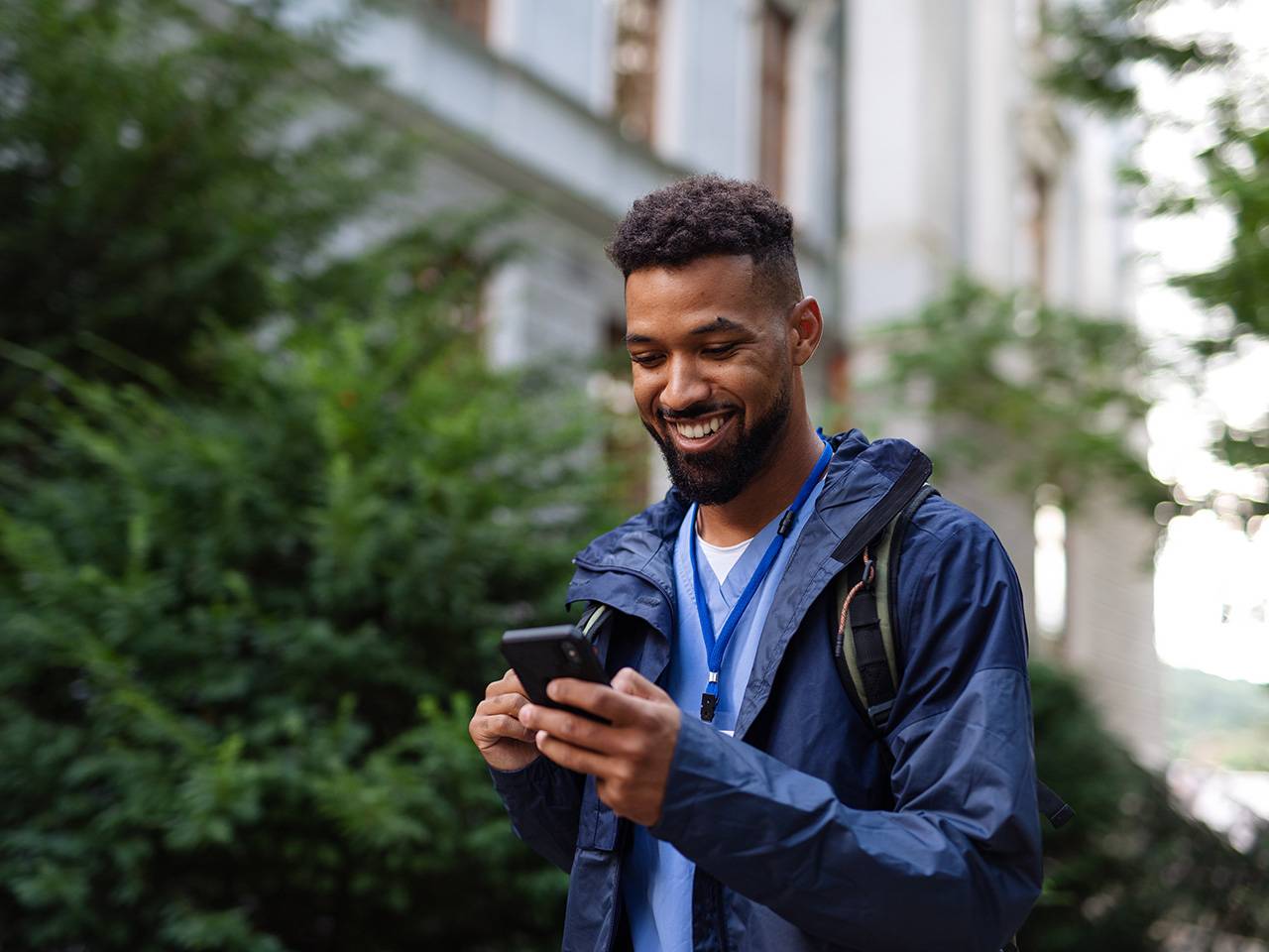 A man is looking at his phone for information as he is walking outside
